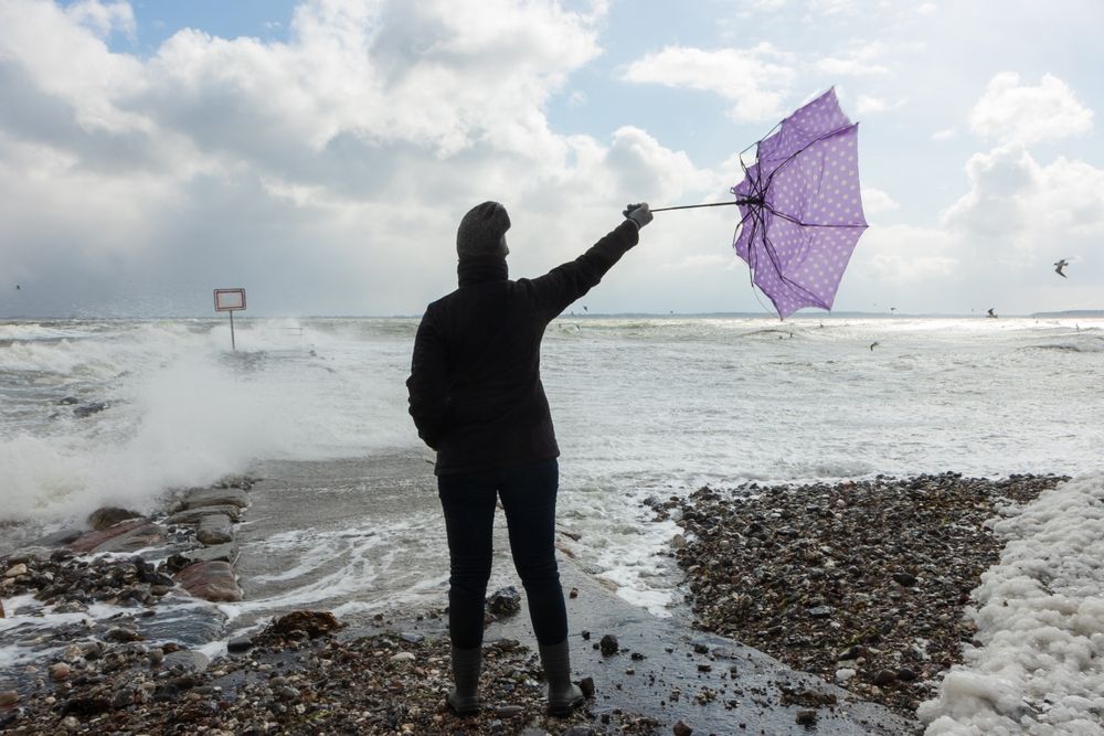 Back,View,Of,A,Woman,Holding,A,Wind,Broken,Umbrella