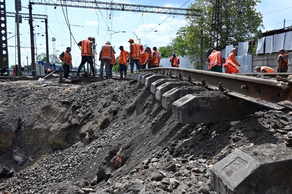 Workers repair damaged railway tracks next to a crater caused by a missile explosion after a shelling in Kharkiv, on May 14, 2023, amid the Russian invasion of Ukraine. (Photo by Sergey BOBOK / AFP)
