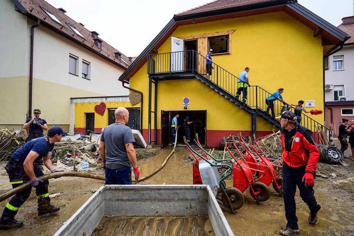 Firemen help local residents to clean houses and streets in flood-hit Crna na Koroskem, on August 9, 2023. Flash floods and landslides that began on August 3, 2023 had submerged large swathes of central and northern Slovenia, cutting off access to villages and disrupting traffic. (Photo by Jure Makovec / AFP)