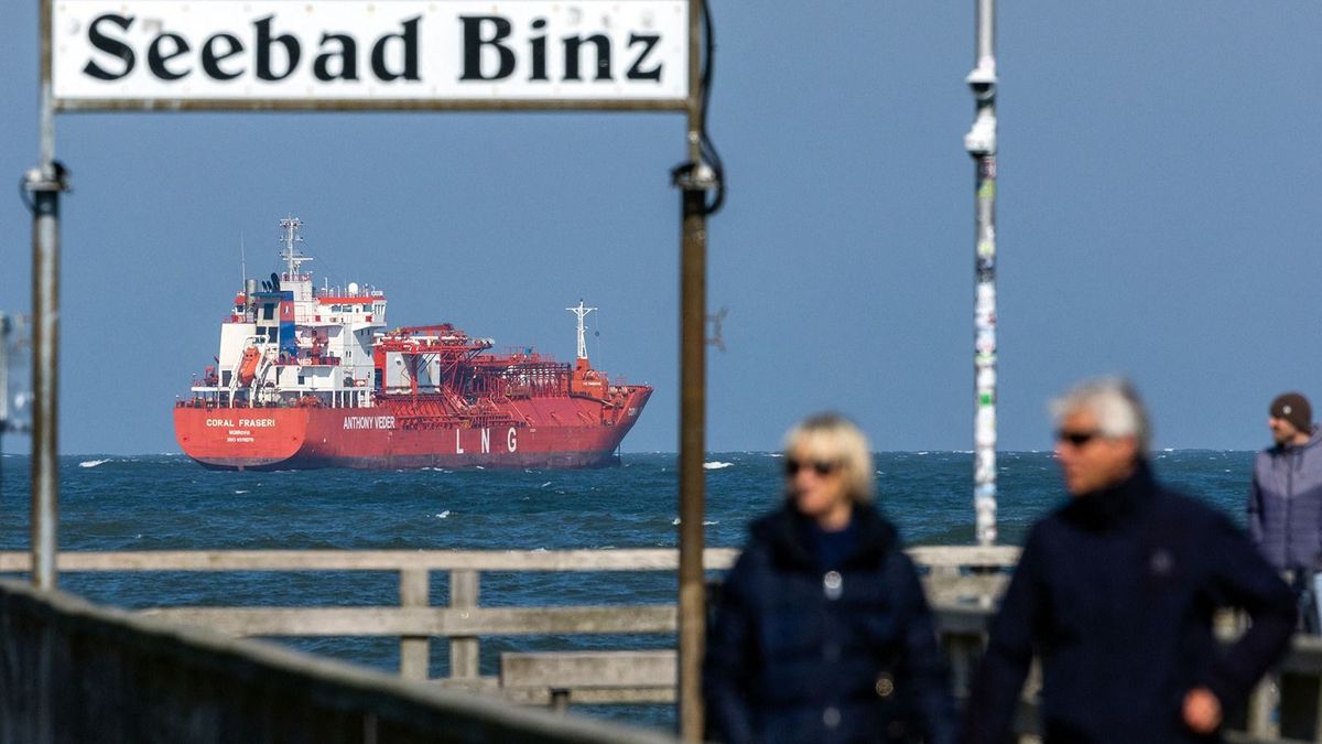 20 April 2023, Mecklenburg-Western Pomerania, Binz: Walkers are on the pier before the meeting of representatives of the German government with associations, mayors and business representatives from Mecklenburg-Western Pomerania against the plans for a liquefied natural gas terminal at the Rügen site. In the background, an LNG tanker can be seen on the Baltic Sea. For weeks, critics of the LNG terminal have been demonstrating against the construction. Under the impression of the energy crisis following the Russian attack on Ukraine, the German government is vigorously pushing ahead with the development of its own import structure for liquefied natural gas (LNG). Photo: Jens Büttner/dpa (Photo by JENS BUTTNER / DPA / dpa Picture-Alliance via AFP)