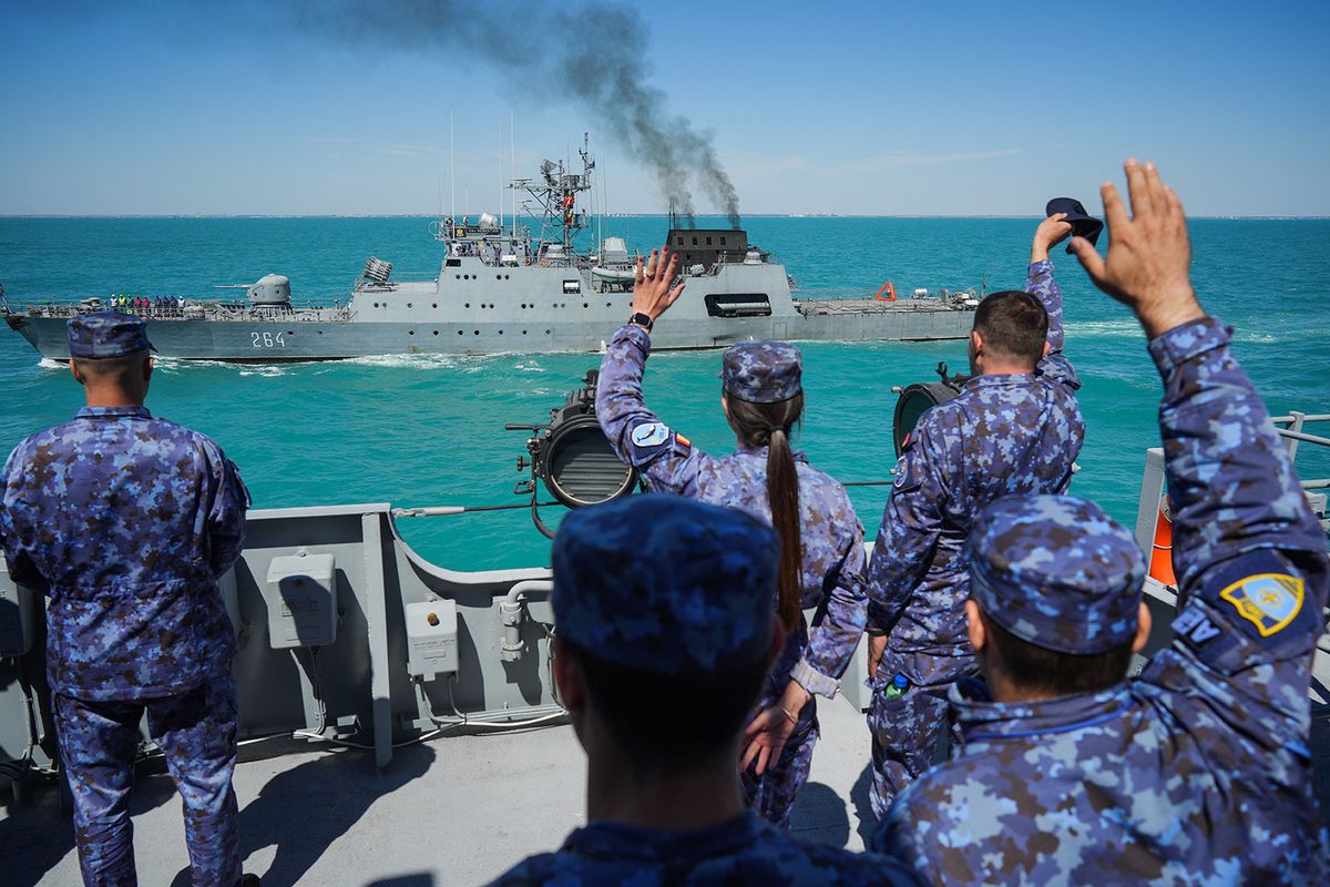 Romanian navy soldiers wave to corvette "RADM Eustatiu Sebastian" from the deck of the "King Ferdinand" frigate during the "Shield Protector" military exercise on the Black Sea, near Constanta, Romania, on June 22, 2022. Around 800 soldiers take part in the annual "Shield Protector" operation, a two-day drill organized by the Romanian Naval Forces, meant to consolidate the NATO combat procedures among the navy military. (Photo by MIHAI BARBU / AFP)