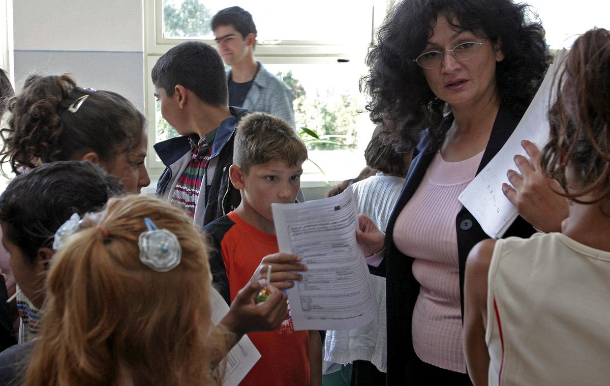 A teacher distributes forms to children in a classroom of the Ghandi school which opened two classes for poor families 02 September 2004 in Zvolen. The Ghandi school is an eight-year-old gymnasium where children from poor families will be able to study. Out of the thirty-nine students enrolled in the two classes, 80% are gypsies.      AFP PHOTO   STR (Photo by AFP)