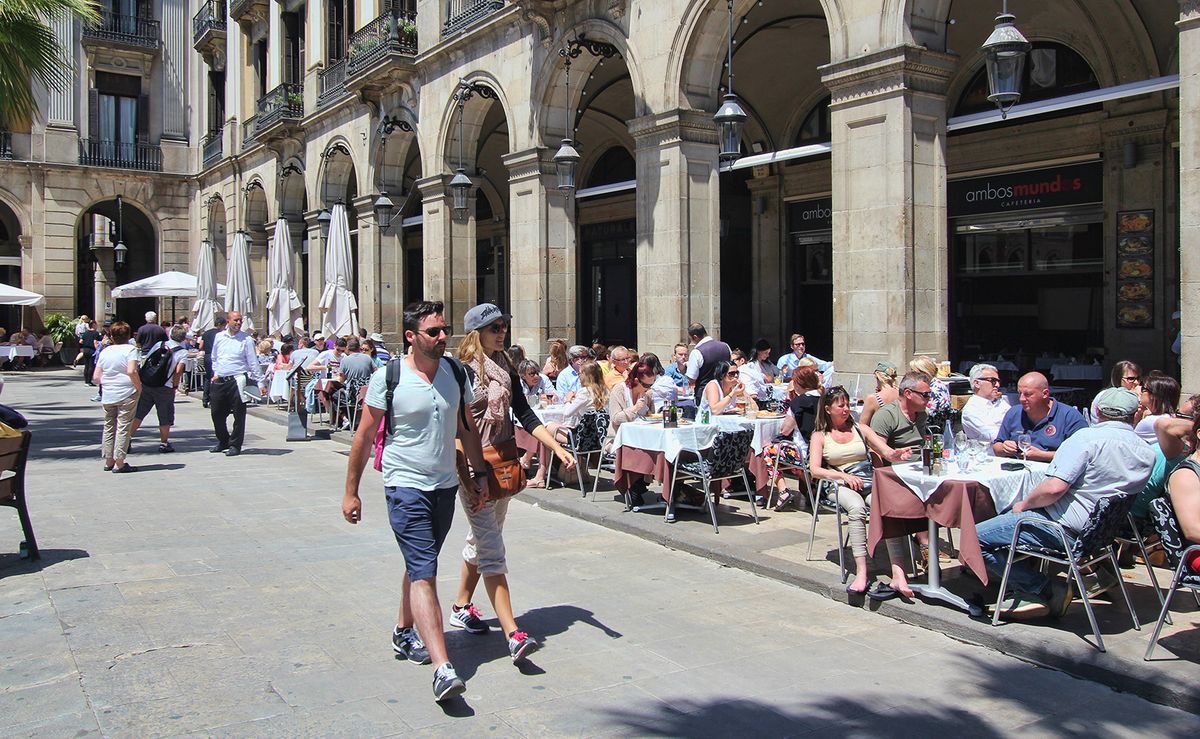 Barcelona, Spain - May 22, 2015: Tourists walk past restaurants on Placa Reial in Barcelona, Spain on May 22, 2015.