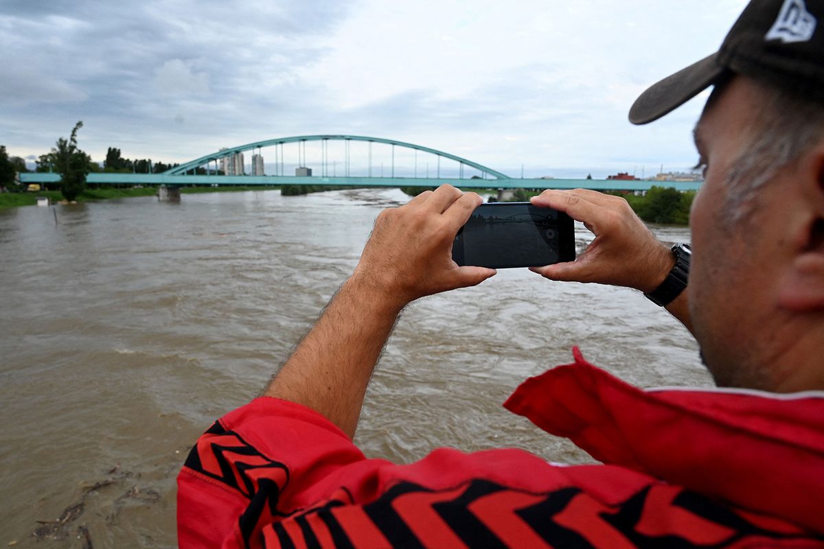 A man takes a photograph of the overflowing Sava river after the river burst it's banks due to heavy rainfall in Zagreb on August 4, 2023. (Photo by DENIS LOVROVIC / AFP)