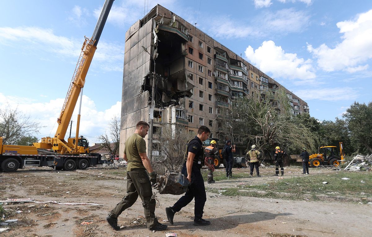 Rescuers carry a fragment of missile outside a nine-storey residential building partially destroyed as a result of Russian missiles strike in Kryvyi Rig on July 31, 2023, amid the Russian invasion of Ukraine. At least four people were killed including a 10-year-old child after a Russian missile attack on the central Ukrainian city of Kryvyi Rig, officials said. (Photo by Anatolii STEPANOV / AFP)