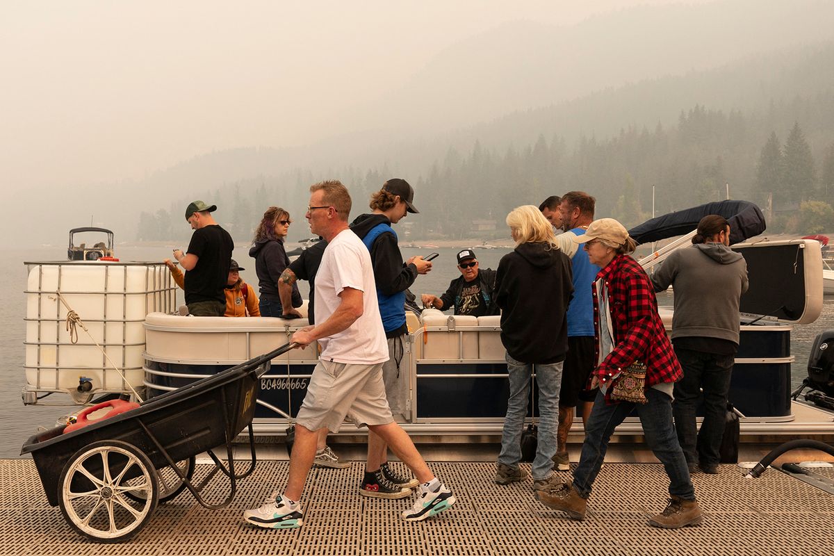 Community members load supplies onto to boats to move across Shuswap Lake for high alert and evacuated community areas that don’t have road access as the Bush Creek East fire continues to burn in Blind Bay, British Columbia, August 21, 2023. Around 30,000 people were under orders from August 19 to evacuate their homes in western Canada's British Columbia, provincial officials said, as a raging wildfire bore down on the city of Kelowna. (Photo by Paige Taylor White / AFP)