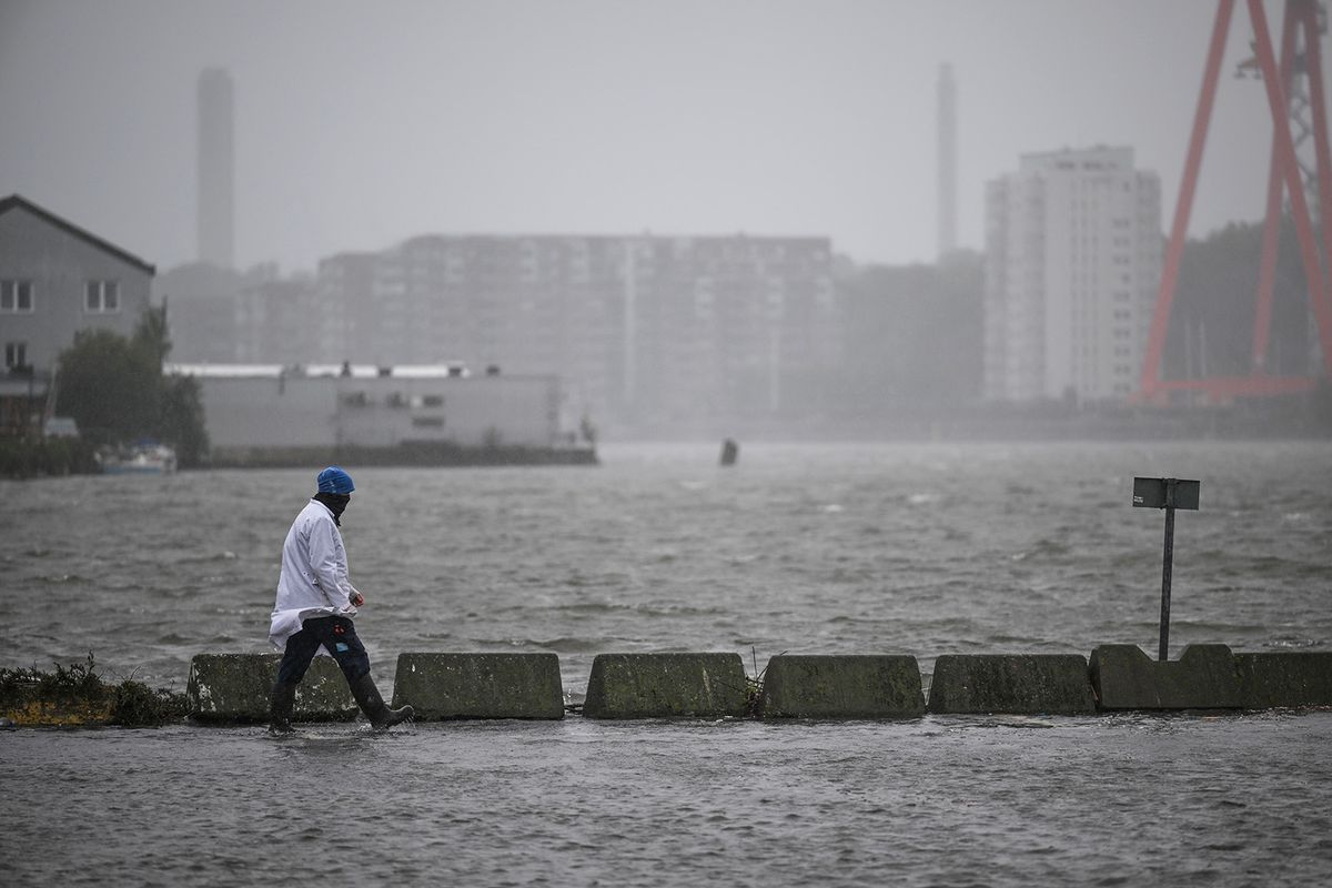 A man walks in the flooded area of the fishing port Fiskhamnen where the Gota Alv river overflowed in Gothenburg, Sweden, on August 08, 2023, after heavy rainfalls as a result of the extreme weather "Hans". Sweden's national weather agency SMHI had issued several "yellow alerts" for Monday, warning of strong winds, floods and heavy rains in multiple parts of the country as extreme weather "Hans" moved in across the country over the weekend. (Photo by Bjorn LARSSON ROSVALL / TT News Agency / AFP) / Sweden OUT