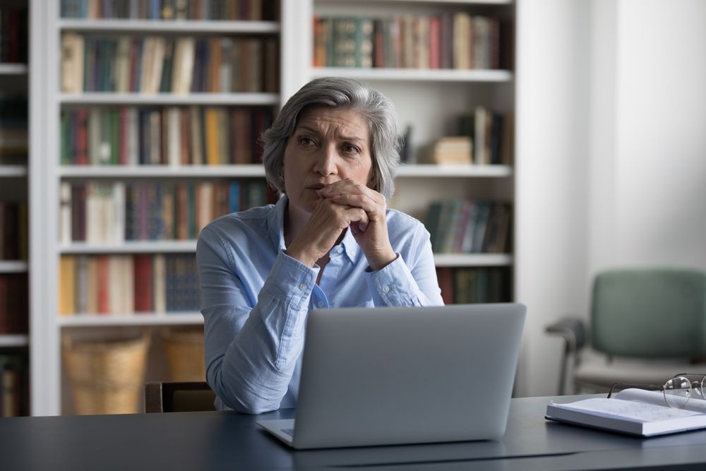 Worried,Pensive,Mature,Business,Woman,Using,Laptop,,Sitting,At,Table