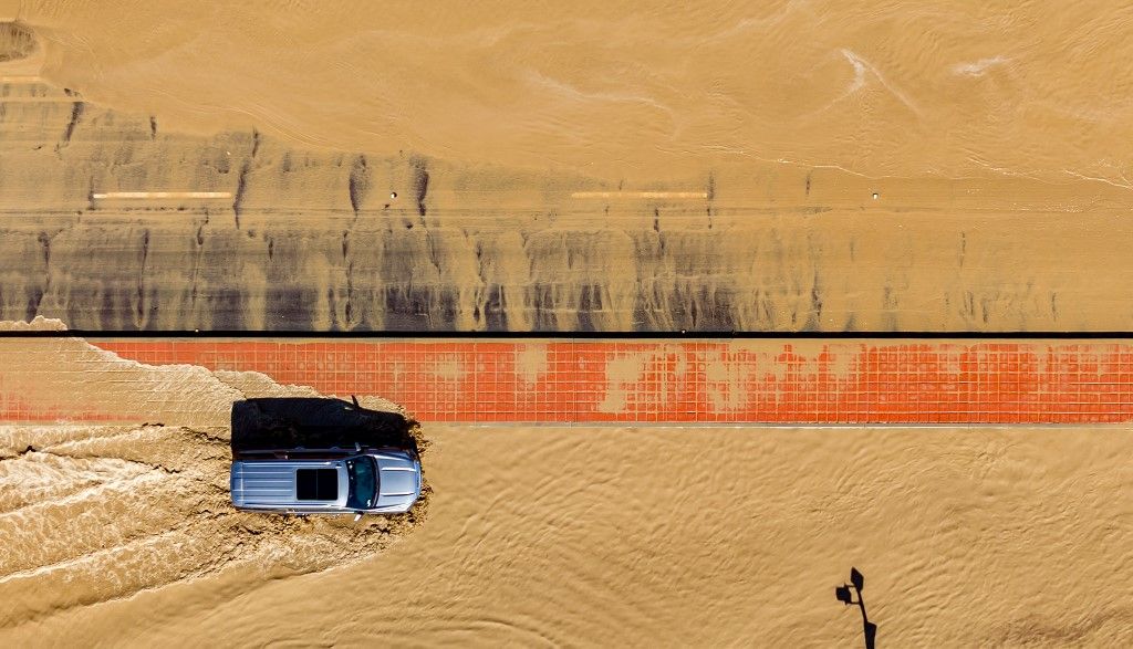 In this aerial picture taken on August 21, 2023 a vehicle drives through floodwaters following heavy rains from Tropical Storm Hilary in Thousand Palms, California. Tropical Storm Hilary drenched Southern California with record rainfall, shutting down schools, roads and businesses before edging in on Nevada on August 21, 2023. California Governor Gavin Newsom had declared a state of emergency over much of the typically dry area, where flash flood warnings remained in effect until this morning. (Photo by JOSH EDELSON / AFP)