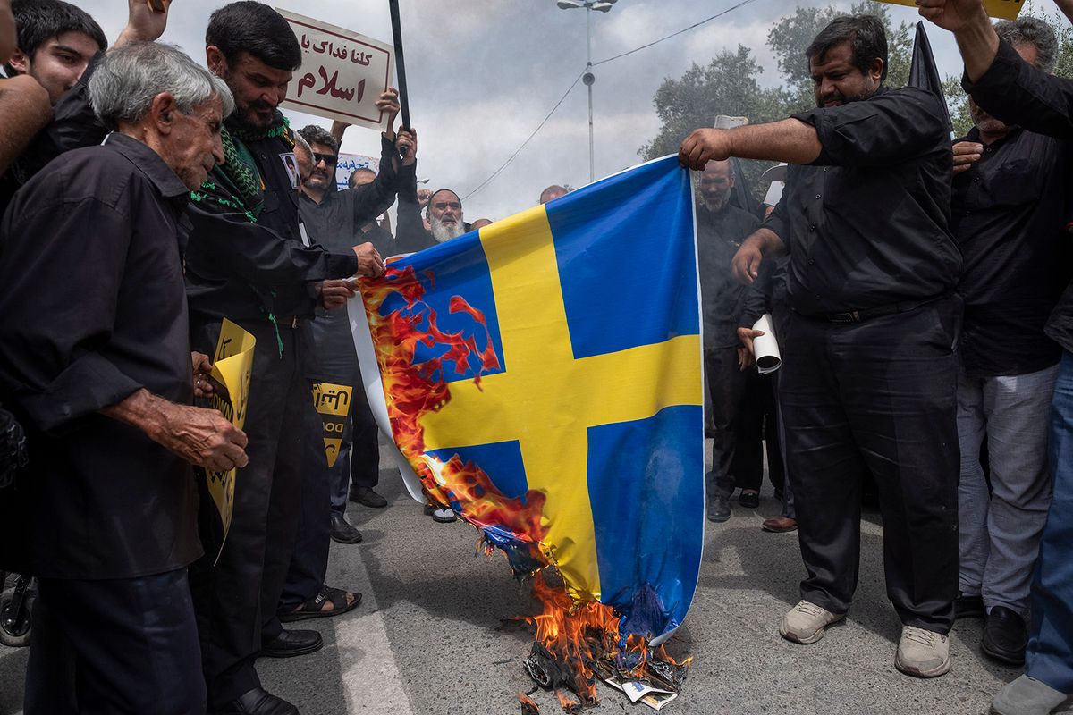 Iranian worshippers burn a Sweden flag during a protest against Koran burning in the Swedish capital Stockholm, at the Imam Khomeini Grand Mosque after Tehran's Friday prayer ceremony, July 21, 2023. (Photo by Morteza Nikoubazl/NurPhoto) (Photo by Morteza Nikoubazl / NurPhoto / NurPhoto via AFP)