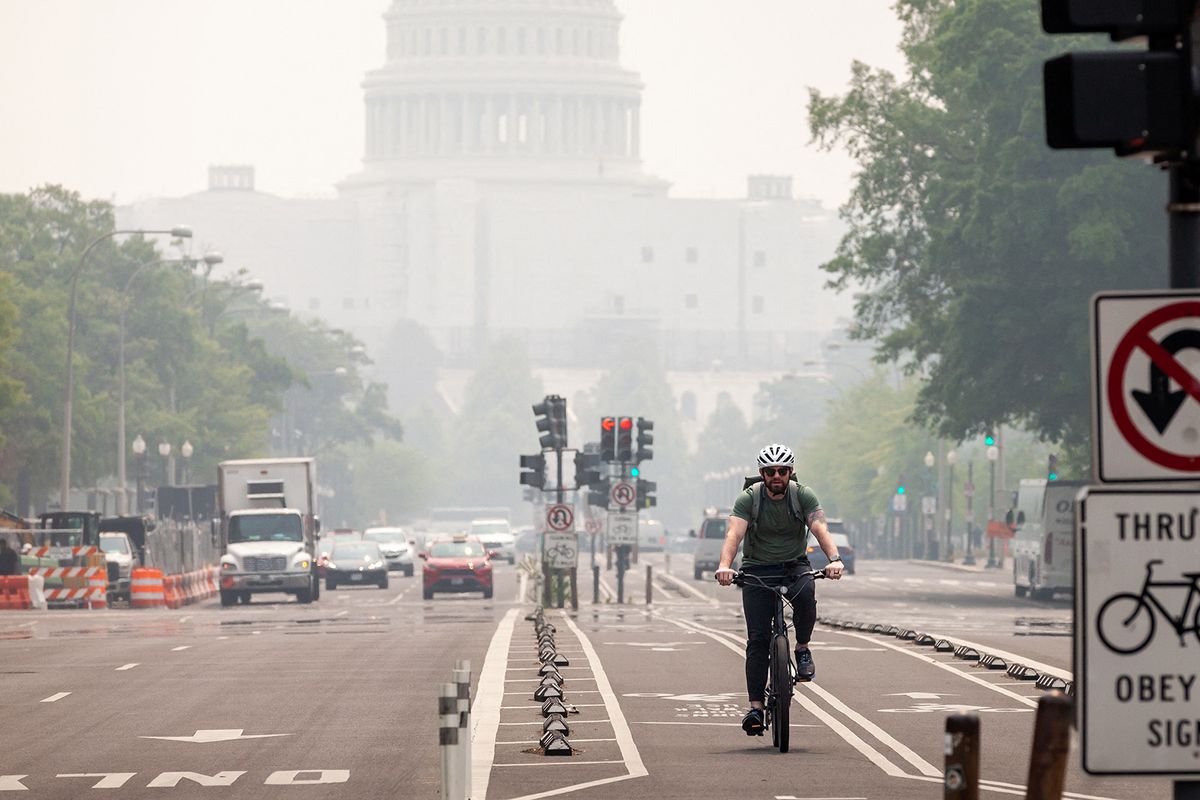 A man cycles down Pennsylvania Avenue only blocks from the Capitol, which is heavily shrouded in haze.  Heavy pollution from wildfires in Canada is blanketing Washington, DC, in haze.  Hundreds of wildfires are burning across Canada, creating hazardous air quality in the Northeast and Mid-Atlantic states. (Photo by Allison Bailey/NurPhoto) (Photo by Allison Bailey / NurPhoto / NurPhoto via AFP)