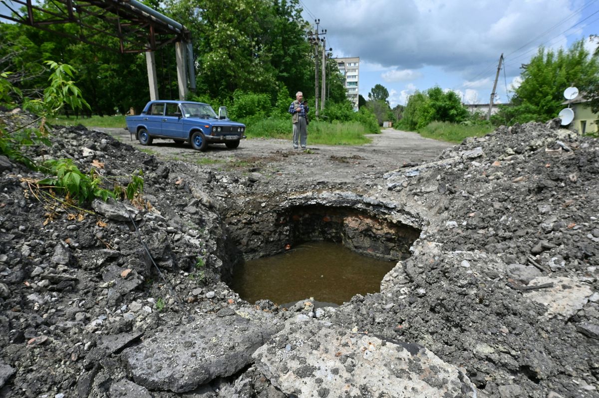 A local resident looks on next to a crater in the centre of Kupiansk, Kharkiv region, on May 26, 2023, amid the Russian invasion of Ukraine. (Photo by SERGEY BOBOK / AFP)