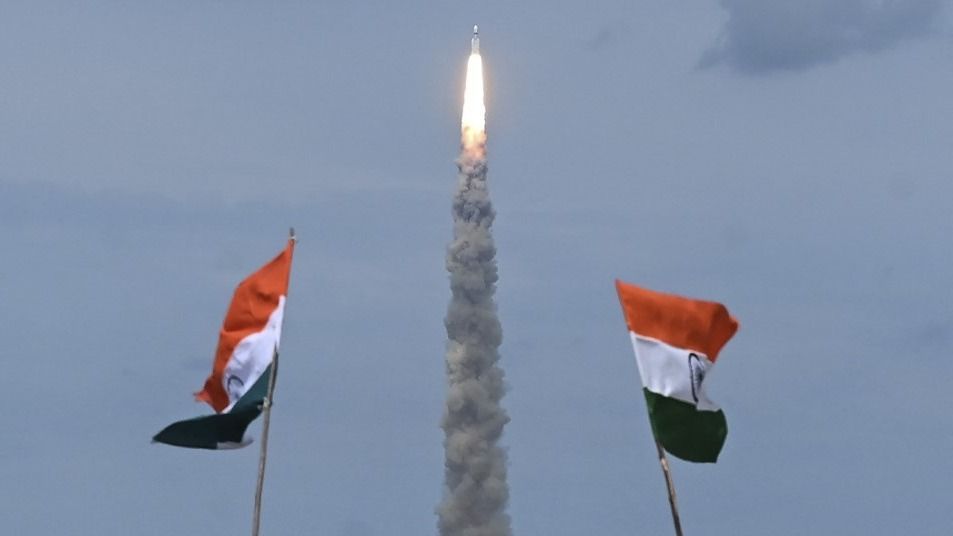 People wave Indian flags as an Indian Space Research Organisation (ISRO) rocket carrying the Chandrayaan-3 spacecraft lifts off from the Satish Dhawan Space Centre in Sriharikota, an island off the coast of southern Andhra Pradesh state on July 14, 2023. India launched a rocket on July 14 carrying an unmanned spacecraft to land on the Moon, its second attempt to do so as its cut-price space programme seeks to reach new heights. (Photo by R.Satish BABU / AFP)