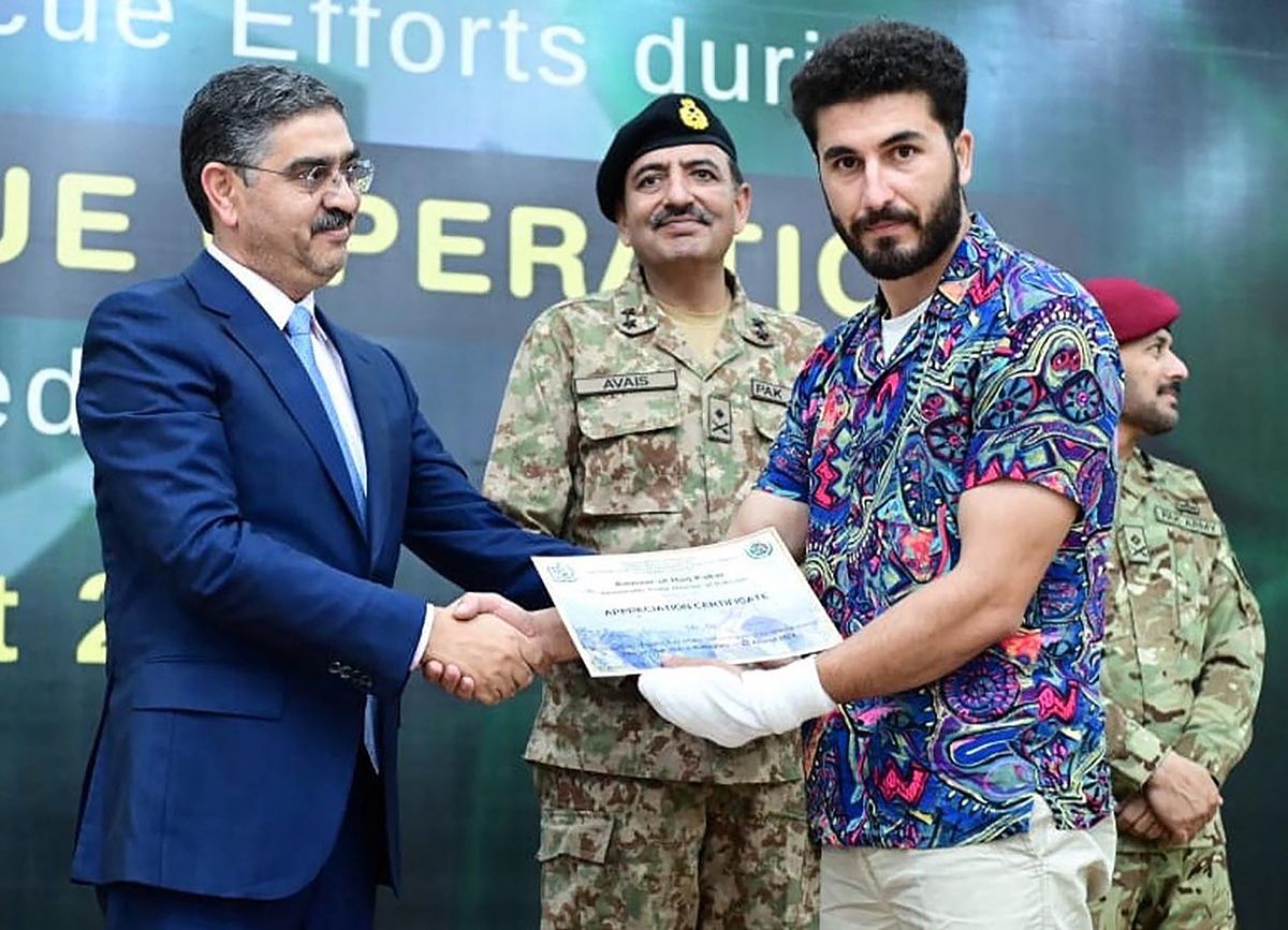 This handout photo taken and released by Pakistan's Press Information Department (PID) on August 24, 2023, shows Pakistani caretaker Prime Minister Anwaar-ul-Haq Kakar (L) presents a certificate to Muhammad Ali Swati, a zipline adventure company owner who was involved in rescuing 6 students in an rescue operation during a ceremony in the honor of rescuers efforts in cable car accident at the Prime Minister office in Islamabad. Six teenage boys were among eight people left stranded hundreds of feet in the air when two of the three chairlift cables snapped on August 22, 2023, leading to a daring rescue mission that brought them to safety. (Photo by PAKISTAN PRESS INFORMATION DEPARTMENT / AFP) / RESTRICTED TO EDITORIAL USE - MANDATORY CREDIT "AFP PHOTO / Pakistan's Press Information Department (PID)  " - NO MARKETING NO ADVERTISING CAMPAIGNS - DISTRIBUTED AS A SERVICE TO CLIENTS