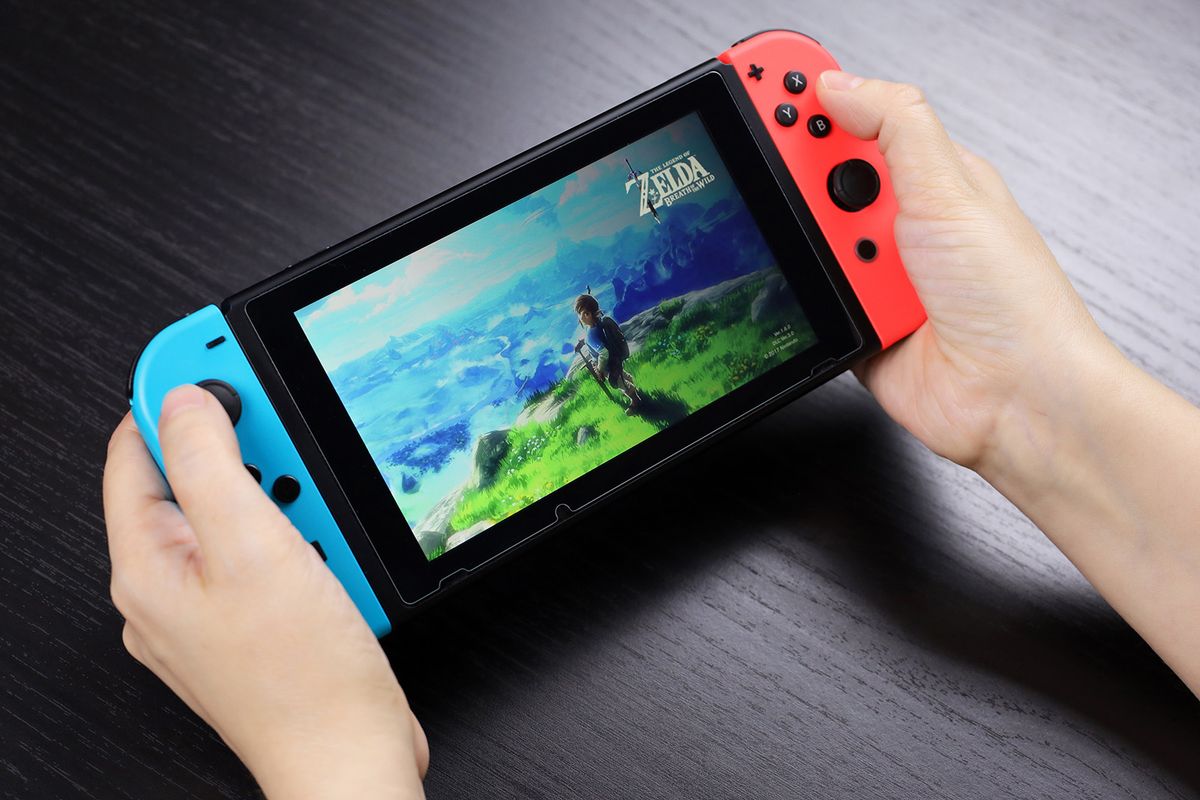 Turkey, Marmaris - December 2022: Defocused view to girl playing The Legend of Zelda game on Nintendo Switch console in handheld mode, selective focus on a screen