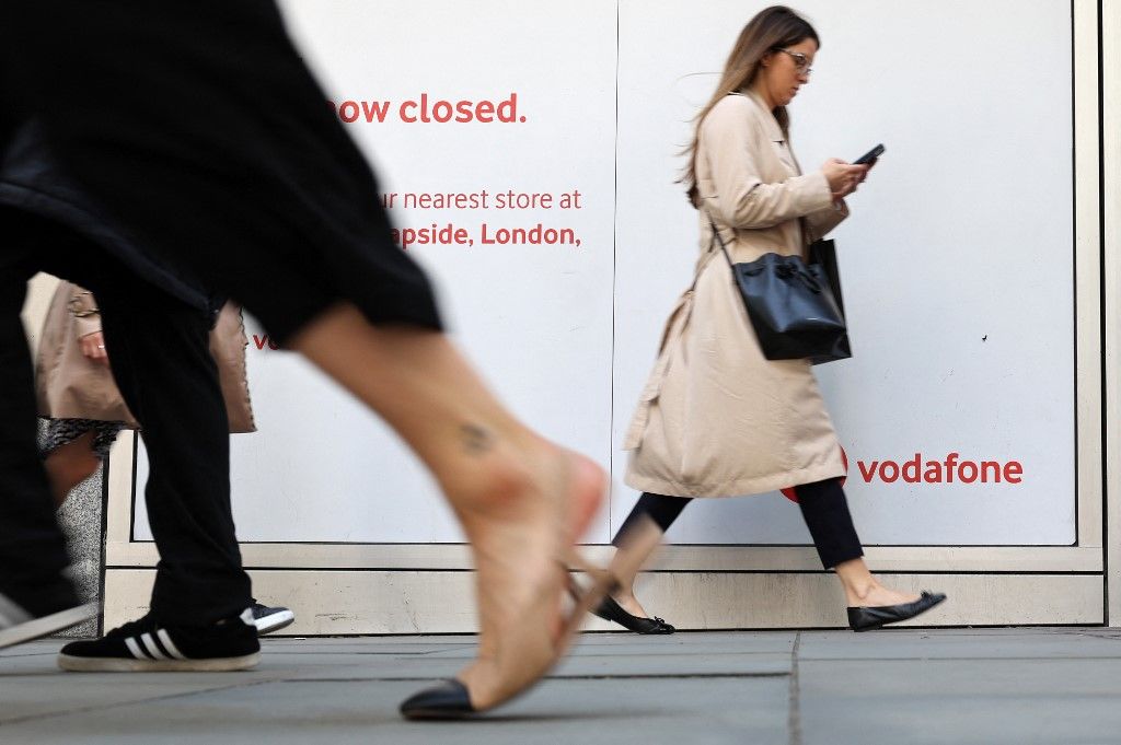 Pedestrians walk past a closed-down Vodafone store in central London on May 16, 2023. British mobile giant Vodafone is to axe 11,000 jobs over three years in the latest cull to hit the tech sector, as new boss Margherita Della Valle slammed recent performance. (Photo by Adrian DENNIS / AFP)
