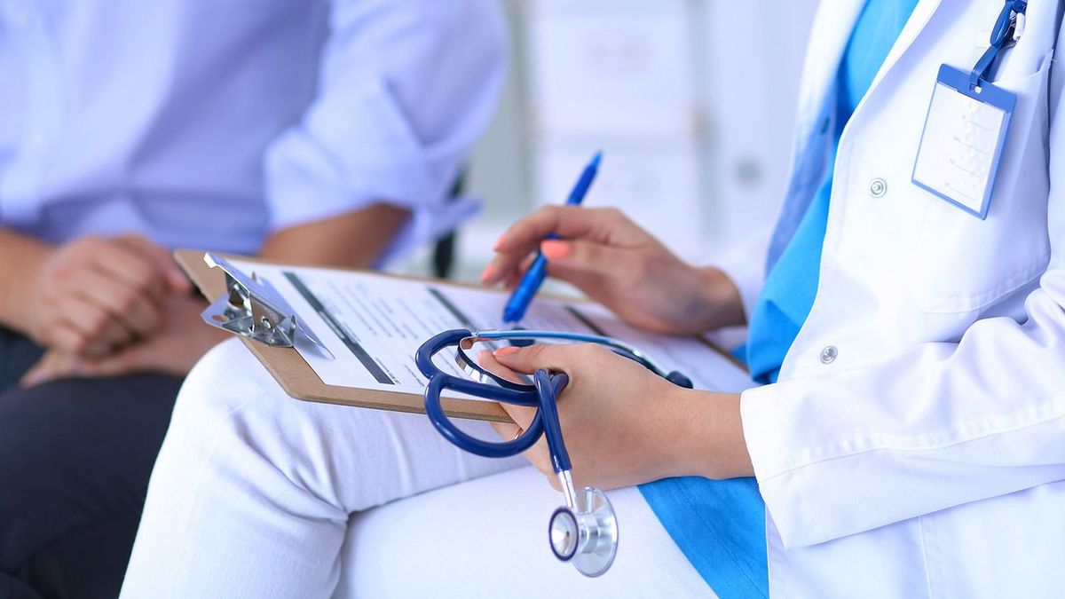 Doctor,Woman,Sitting,With,Male,Patient,At,The,Desk