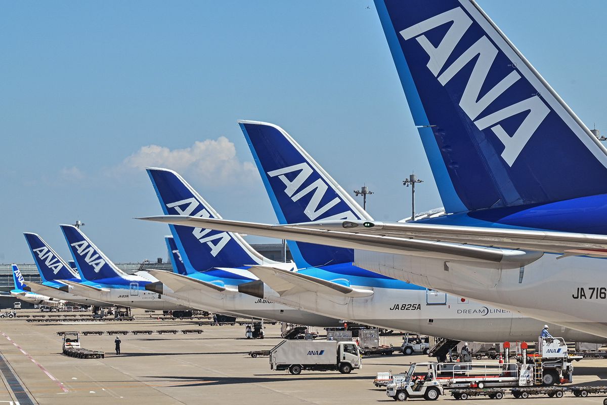 This photo taken on July 23, 2023 shows a worker (bottom L) on the tarmac behind a line of planes for Japanese airline All Nippon Airways (ANA) at Tokyo International Airport at Haneda in Tokyo. ANA Holdings are expected to announce first quarter earnings on July 28. (Photo by Richard A. Brooks / AFP)