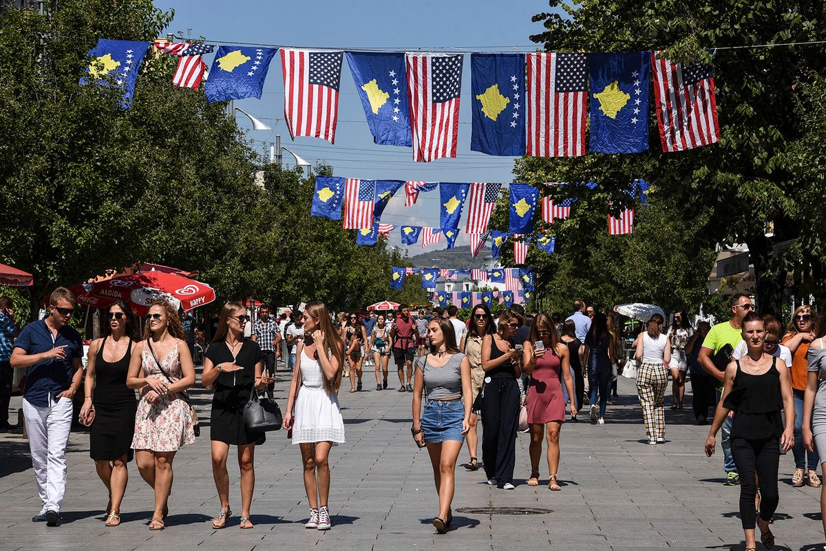 Kosovo Albanians walk through the Mother Teresa square decorated with Kosovo and US flags ahead of the visit of the United States Vice President Joe Biden, in Pristina on August 16, 2016. US Vice President Joe Biden starts a visit to the Balkans in Belgrade, where he will meet Serbian President Tomislav Nikolic and Prime Minister Aleksandar Vucic. (Photo by ARMEND NIMANI / AFP)