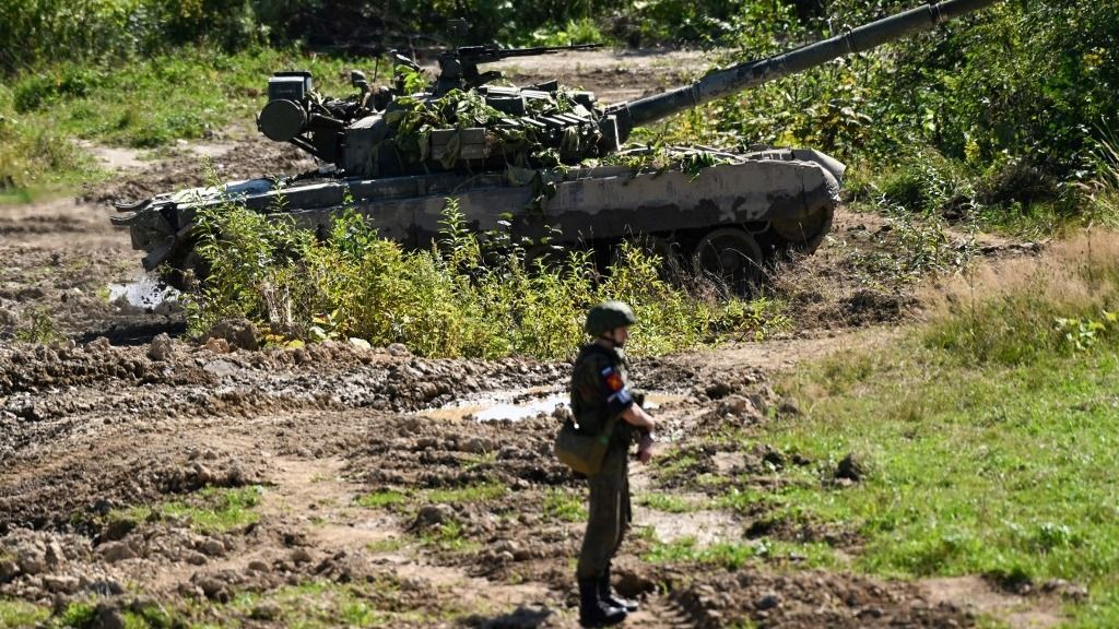 A serviceman looks on by a Russian T-80 tank while taking part in the 'Vostok-2022' military exercises at the Uspenovskyi training ground (Sakhalin Island) outside the city of Yuzhno-Sakhalinsk on the Russian Far East on September 4, 2022. The Vostok 2022 military exercises, involving several Kremlin-friendly countries including China, takes place from September 1-7 across several training grounds in Russia's Far East and in the waters off it. Over 50,000 soldiers and more than 5,000 units of military equipment, including 140 aircraft and 60 ships, are involved in the drills. (Photo by Kirill KUDRYAVTSEV / AFP)