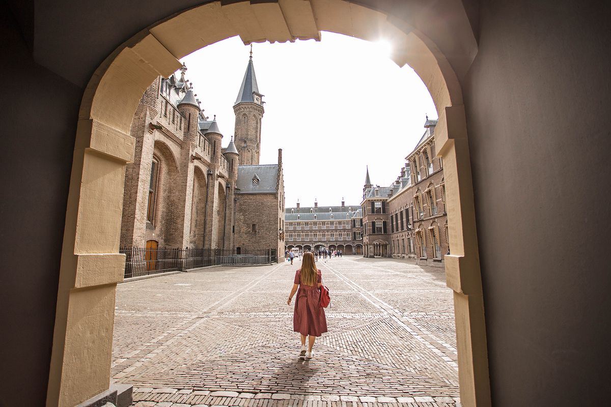 Beautiful,View,Through,The,Arch,To,The,Medieval,Binnenhof,Castle.Beautiful view through the Arch to the medieval Binnenhof castle. Young woman walk in the Binnenhof palace courtyard. The Hague, The Netherlands.