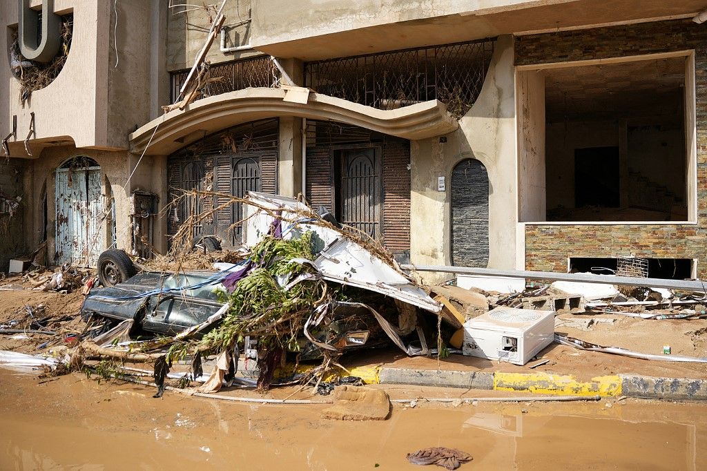 This handout picture provided by the office of Libya's Benghazi-based interim prime minister on September 11, 2023 shows a view of a destroyed vehicle by damaged buildings in the eastern city of Derna, about 290 kilometres east of Benghazi, in the wake of the Mediterranean storm "Daniel". At least 150 people were killed when freak floods hit eastern Libya, officials said on September 11, after the storm's torrential rains battered Turkey, Bulgaria, and Greece. (Photo by The Press Office of Libyan Prime Minister / AFP) / === RESTRICTED TO EDITORIAL USE - MANDATORY CREDIT "AFP PHOTO / HO /MEDIA OFFICE OF LIBYAN PRIME MINISTER (BENGHAZI)" - NO MARKETING NO ADVERTISING CAMPAIGNS - DISTRIBUTED AS A SERVICE TO CLIENTS ===