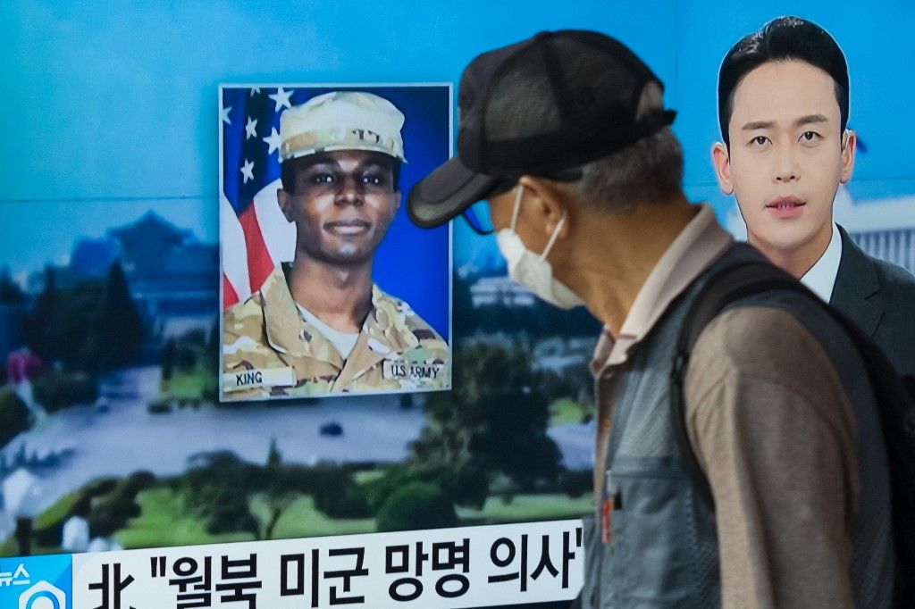 In this photo taken in Seoul on August 16, 2023, a man walks past a television showing a news broadcast featuring a photo of US soldier Travis King (C), who ran across the border into North Korea while part of a tour group visiting the Demilitarized Zone on South Korea's border on July 18. Travis King defected to North Korea to escape "mistreatment and racial discrimination in the US Army", state media said Wednesday, Pyongyang's first official confirmation they were holding the American soldier. (Photo by Anthony WALLACE / AFP)