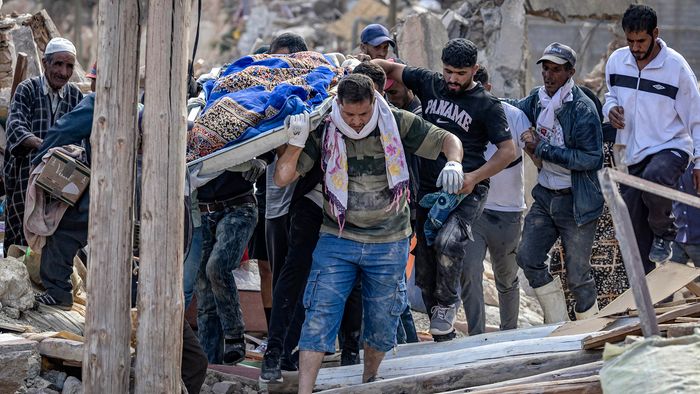 People carry the remains of a victim of the deadly 6.8-magnitude September 8 earthquake, in the village of Imi N'Tala near Amizmiz in central Morocco on September 10, 2023. Using heavy equipment and even their bare hands, rescuers in Morocco on September 10 stepped up efforts to find survivors of a devastating earthquake that killed more than 2,100 people and flattened villages. (Photo by FADEL SENNA / AFP)