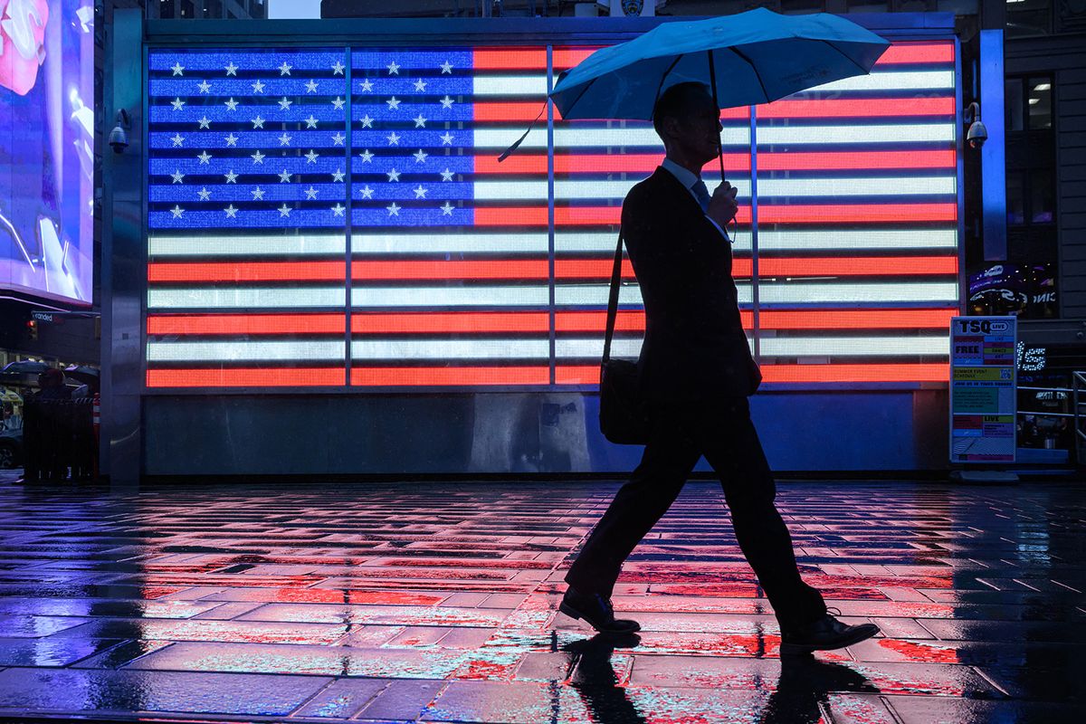 Pedestrians shelter beneath umbrella as they walk along a street during rain in Times Square, New York on September 26, 2023. (Photo by Ed JONES / AFP)