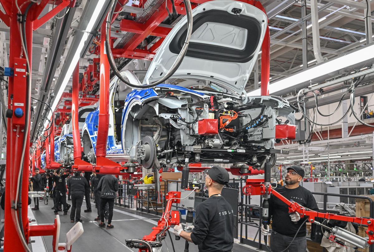 20 March 2023, Brandenburg, Grünheide: Employees of the Tesla Gigafactory Berlin Brandenburg work on a production line of a Model Y electric vehicle. The Tesla plant was opened and put into operation on March 22, 2022. In the meantime, about 10,000 people are employed there. (to dpa "One year of Tesla plant in Germany - showcase factory and object of dispute") Photo: Patrick Pleul/dpa (Photo by PATRICK PLEUL / DPA / dpa Picture-Alliance via AFP)
