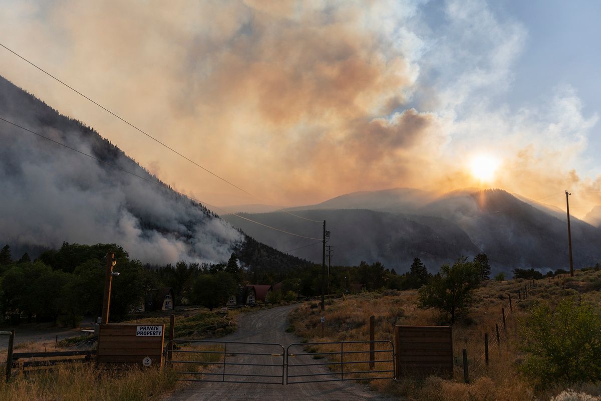 (FILES) The Crater Creek Fire burns in the background of Keremeos Village on the same day that the Province of British Columbia declared a Provincial State of Emergency, in British Columbia, Canada, on August 18, 2023. Ottawa estimates the annual cost of fighting wildfires at Can$1 billion, and noted that, according to the Canadian Climate Institute, climate impacts such as more and bigger fires could halve Canada's projected economic growth in the coming years. Most worrying, he said, is that Canadians aren't dealing anymore with one localized disaster every few years or decades, but rather "several events stacked on top of each other in a single year" -- including fires, floods, heatwaves and powerful storms. (Photo by Paige Taylor White / AFP)