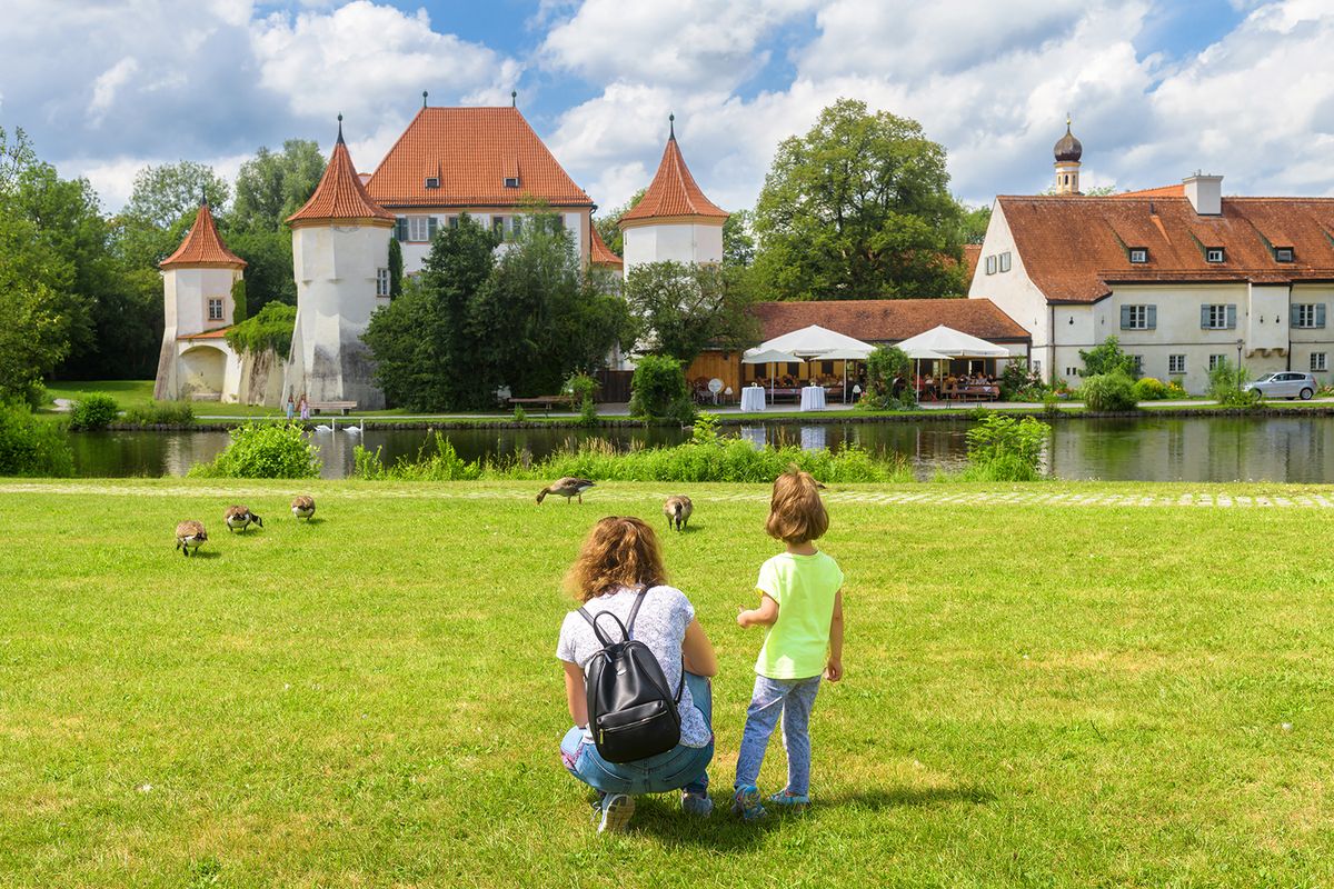 Kid,Walks,On,Green,Meadow,By,Old,Blutenburg,Castle,,Munich,
Kid walks on green meadow by old Blutenburg Castle, Munich, Bavaria, Germany. Family in city park in summer. This place is tourist attraction of Munich. Woman and child near medieval houses in Munich.