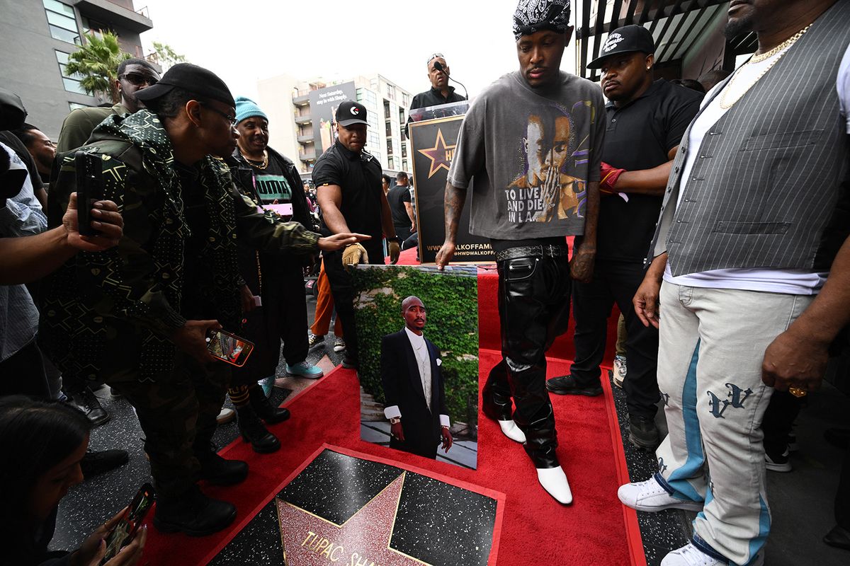 US rapper YG holds a portrait of US rapper Tupac Shakur, during Tupac's Hollywood Walk of Fame star ceremony in Hollywood, California, on June 7, 2023. Slain rap legend Tupac Shakur was honored with a star on Hollywood's Walk of Fame on Wednesday, almost three decades after the best-selling artist was gunned down in a drive-by shooting. The ceremony paid tribute to a rapper who died at age 25 after a brief but spectacular career, in which he went from backup dancer to self-styled gangsta and one of the most influential figures in hip-hop. (Photo by Robyn Beck / AFP)