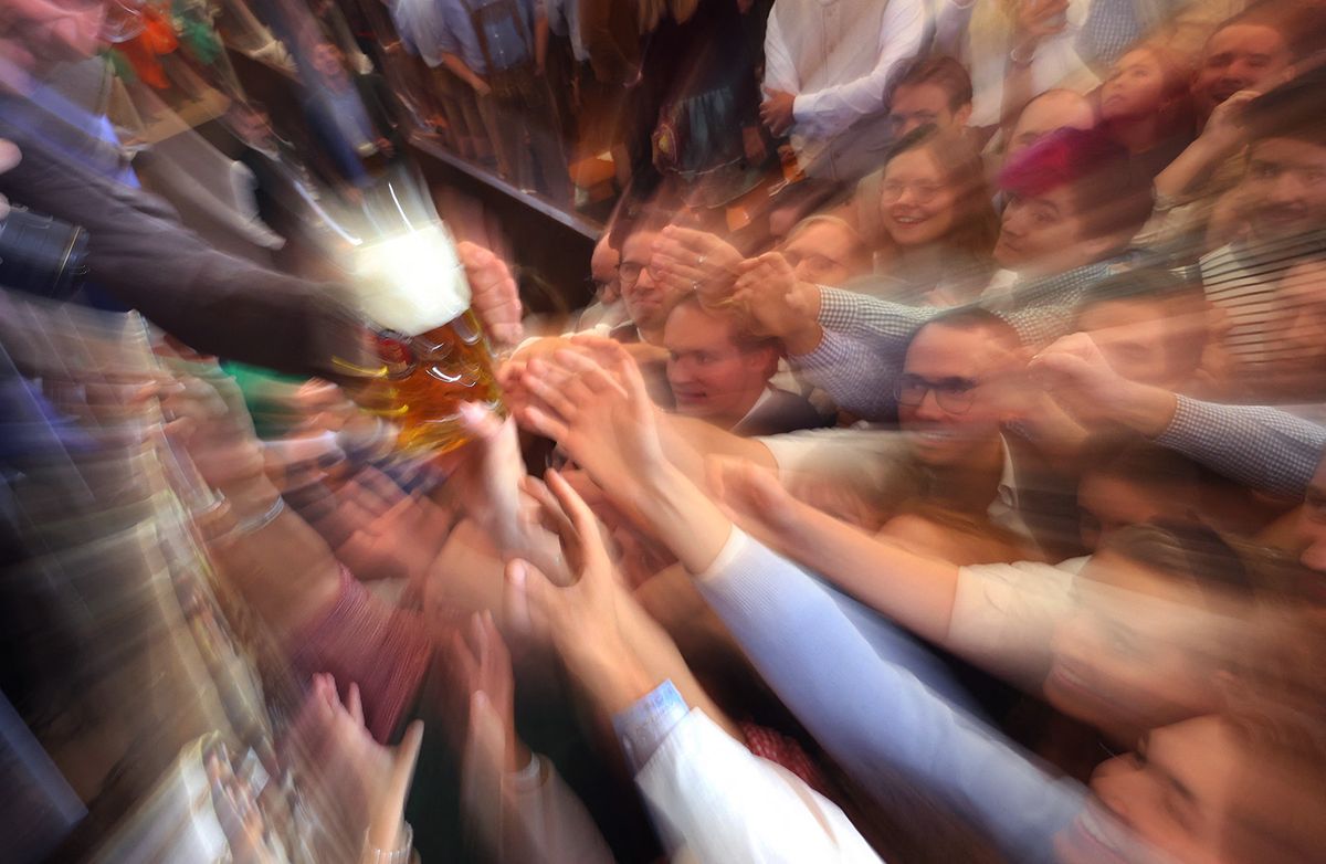 17 September 2022, Bavaria, Munich: Oktoberfest visitors try to grab a Maß Bier after the tapping in the Paulaner festival tent. Photo: Karl-Josef Hildenbrand/dpa (Photo by KARL-JOSEF HILDENBRAND / DPA / dpa Picture-Alliance via AFP)