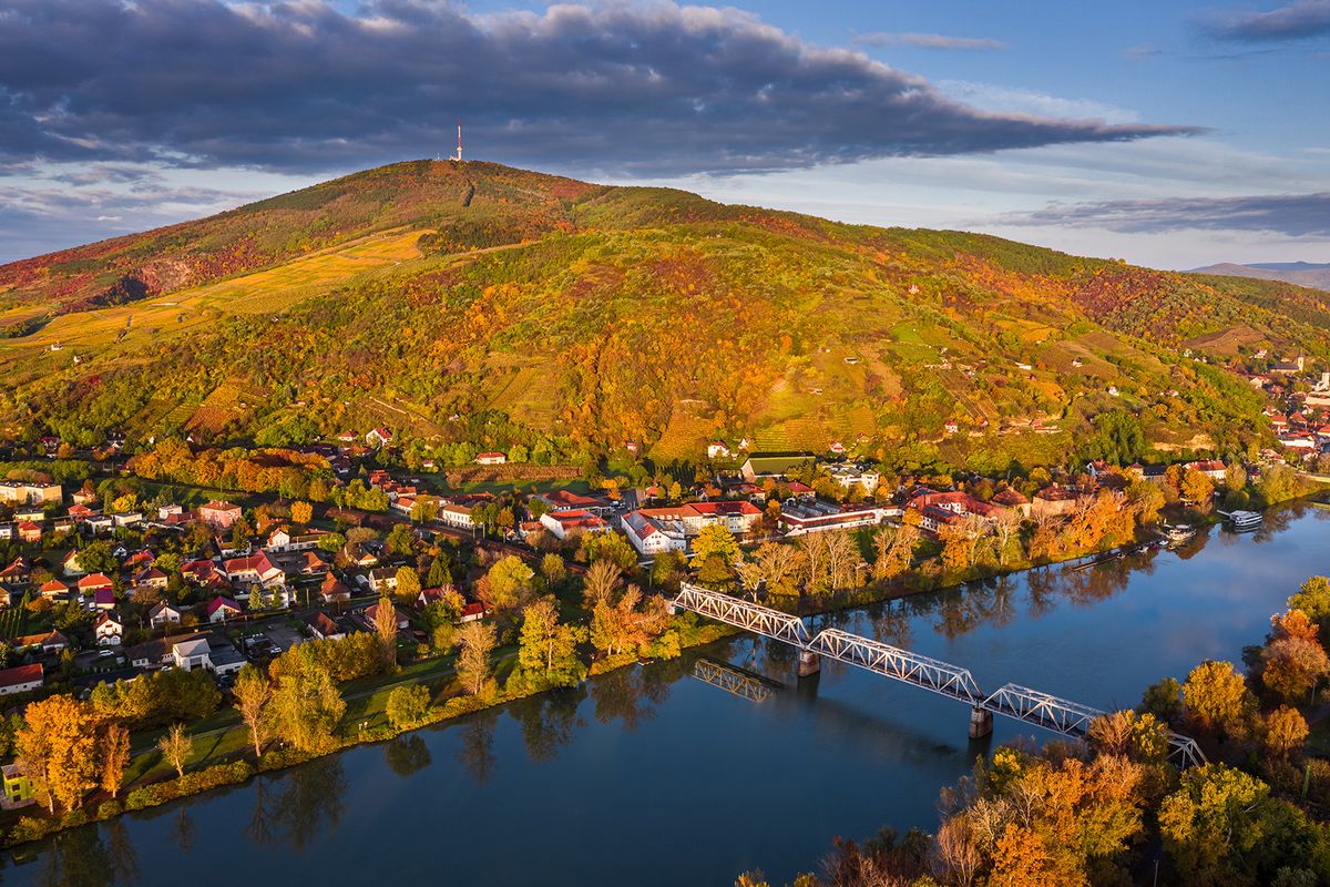 Tokaj, Hungary - Aerial panoramic view of the small town of Tokaj with golden vineyards on the hills of wine region on a warm sunny autumn morning. River Tisza and blue sky and clouds 