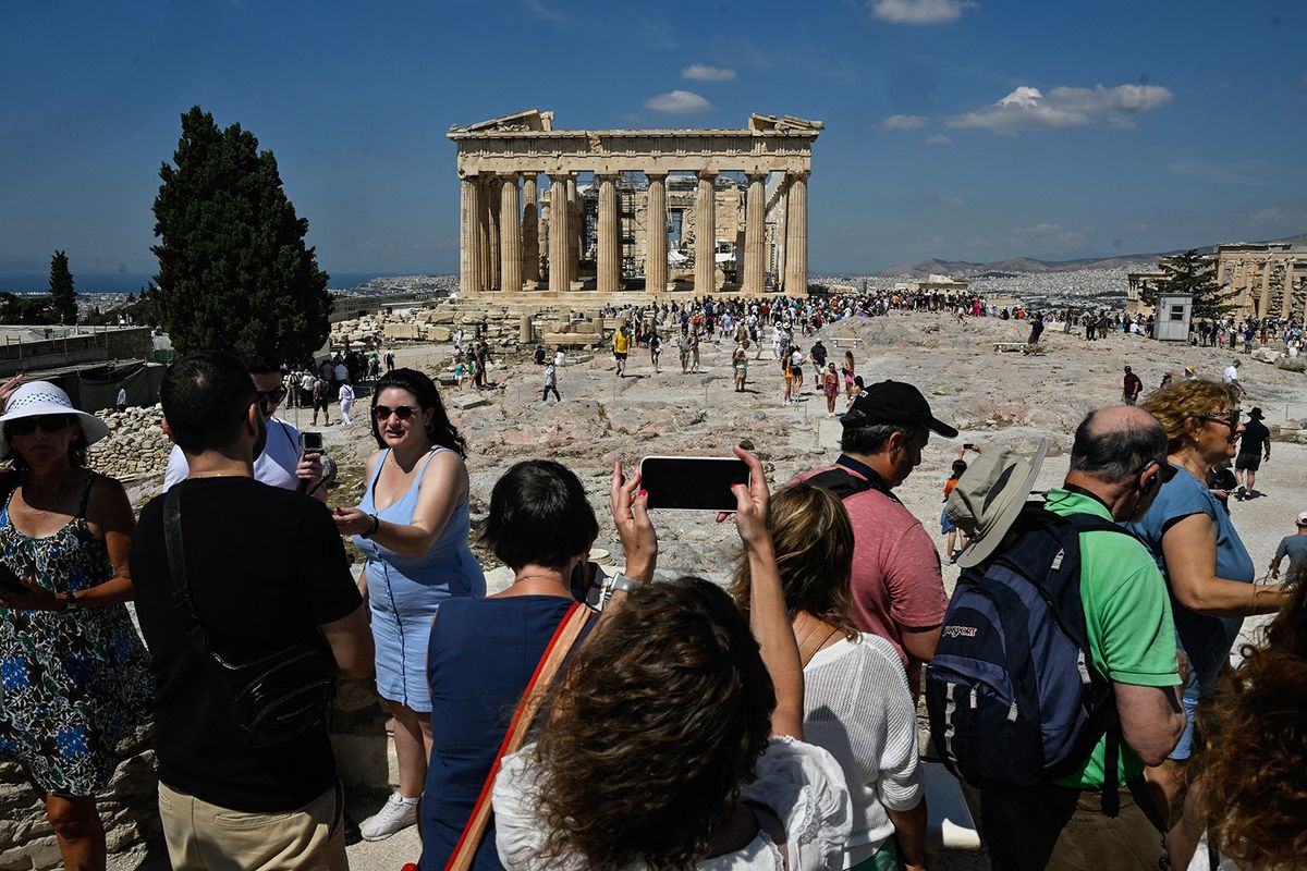 Tourists take photos and selfies ifront of the Parthenon Temple during their visit at the Acropolis archaeological site in Athens on June 14, 2023. "The wait and the amount of people that are here are definitely overwhelming," a customer services operator told AFP.World Heritage Watch, a non-governmental organisation which supports UNESCO in protecting and safeguarding sites of international value, notes that the Acropolis currently lacks visitor management plans required under the UN watchdog's World Heritage Convention, to which Greece is a signatory. (Photo by Louisa GOULIAMAKI / AFP)