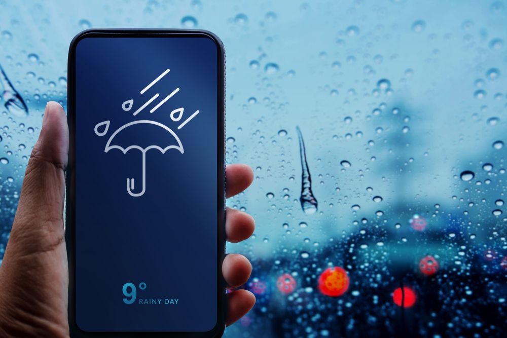 Rainy,Day,Concept.,Hand,Holding,Smartphone,With,Weather,Information,Show