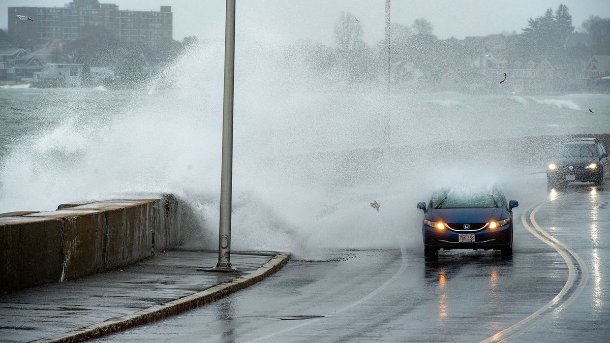 Waves crash over the sea wall and onto cars as they drive in Winthrop, Massachusetts, on March 14, 2023. The nor’easter storm brought high winds that created large waves which caused minor costal flooding. (Photo by Joseph Prezioso / AFP)