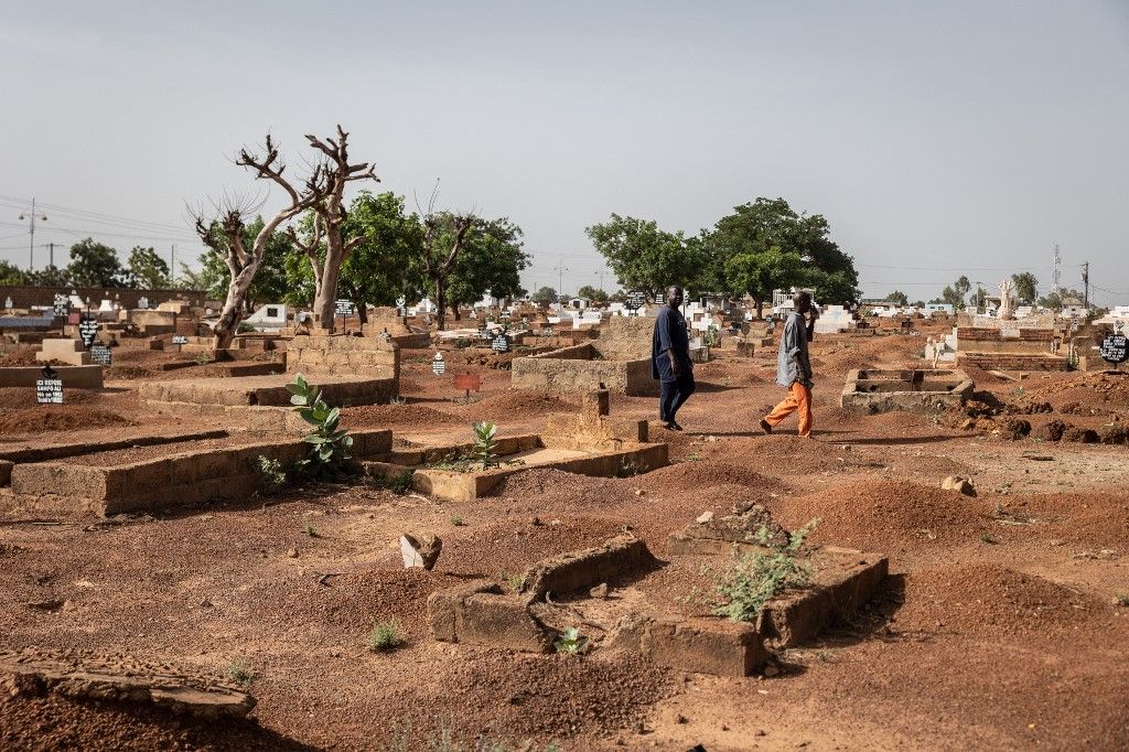 Men walk through the Nagrin cemetery, in Ouagadougou, on June 19, 2023. Gutted graves, drowned in garbage and tall grass, no sign at the entrance, no door: the majority of abandoned cemeteries in Ouagadougou have become dens for delinquents. But one zealous citizen decided to take matters into his own hands. (Photo by OLYMPIA DE MAISMONT / AFP)