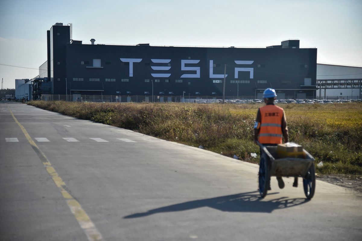 A worker walks on a road next to the new Tesla factory built in Shanghai on November 8, 2019. (Photo by HECTOR RETAMAL / AFP)