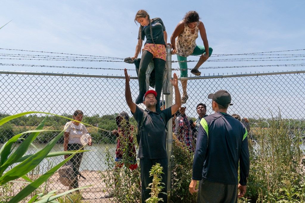 Migrants' perilous trip past buoys, razor wire to reach TexasMigrants help each other climb over a barbed wire fence into the US from Mexico, in Eagle Pass, Texas, on August 25, 2023. With their two children on their shoulders, Wilfredo and Nataly jump into the Rio Grande from the Mexican shore. The water is up to their waists. They avoid the line of buoys that the state of Texas placed to block their passage and head for the United States. They cross from Piedras Negras, Coahuila state, and seek the opposite bank in Eagle Pass, a city in southern Texas whose governor, Republican Greg Abbott, has militarized the river to contain the entry of migrants. (Photo by SUZANNE CORDEIRO / AFP)