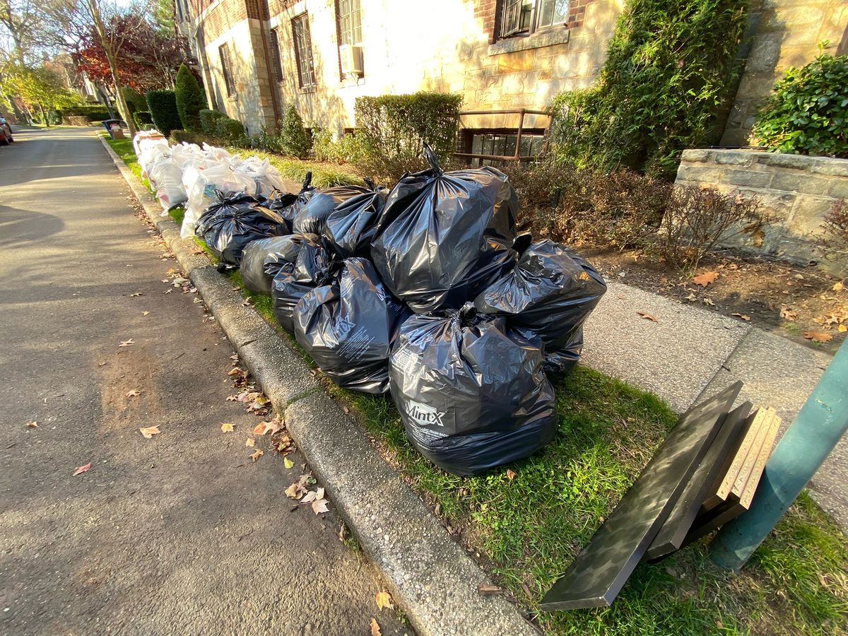 MintX Bags of trash and recyclables stacked along the curb waiting for pick up in Queens, New York