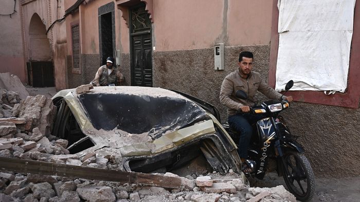 A man rides a motorcycle past rubble in the old quarters of Marrakesh on September 10, 2023, two days after a devastating 6.8-magnitude earthquake struck the country. Moroccans on September 10 mourned the victims of a devastating earthquake that killed more than 2,000 people as rescue teams raced to find survivors trapped under the rubble of flattened villages. (Photo by Philippe LOPEZ / AFP)