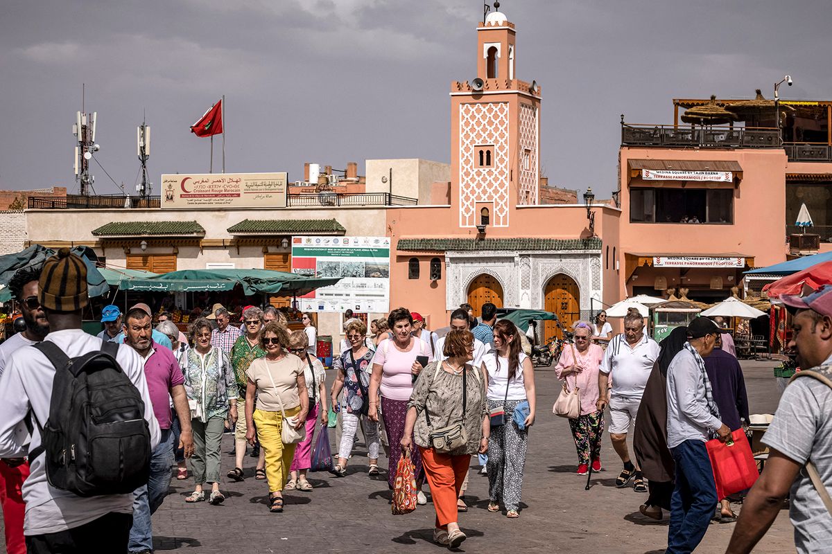 Tourists walk about in Jemaa el-Fnaa square in Morocco's Marrakesh on May 12, 2022. Marrakech, the Morocco's tourist showcase at the foot of the High Atlas mountain range, is gradually recovering from two long years of covid restrictions which devastated the sector that accounted for nearly seven percent of the natioanl GDP in 2019. Only 3.7 million foreign tourists visited the North African kingdom in 2021 compared to 13 million in 2019, according to official statistics. But in May 2022, the narrow streets of the old medina, a UNESCO World Heritage site, are teeming with people. (Photo by FADEL SENNA / AFP)