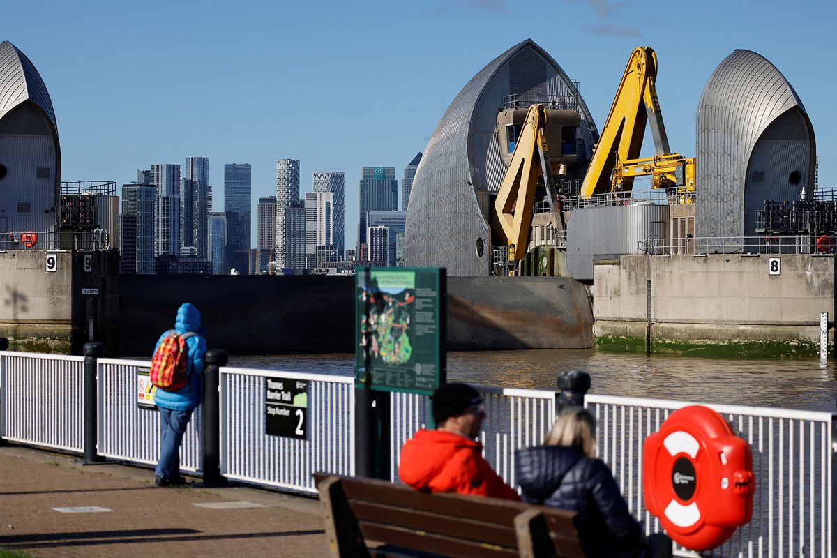 People watch as the Thames Barrier is closed for the 200th time since becoming operational in 1982, to help protect London from potential flooding due to a high tide as a result of low pressure and northerly winds coinciding with spring tides, in central London on October 21, 2021. (Photo by Tolga Akmen / AFP)