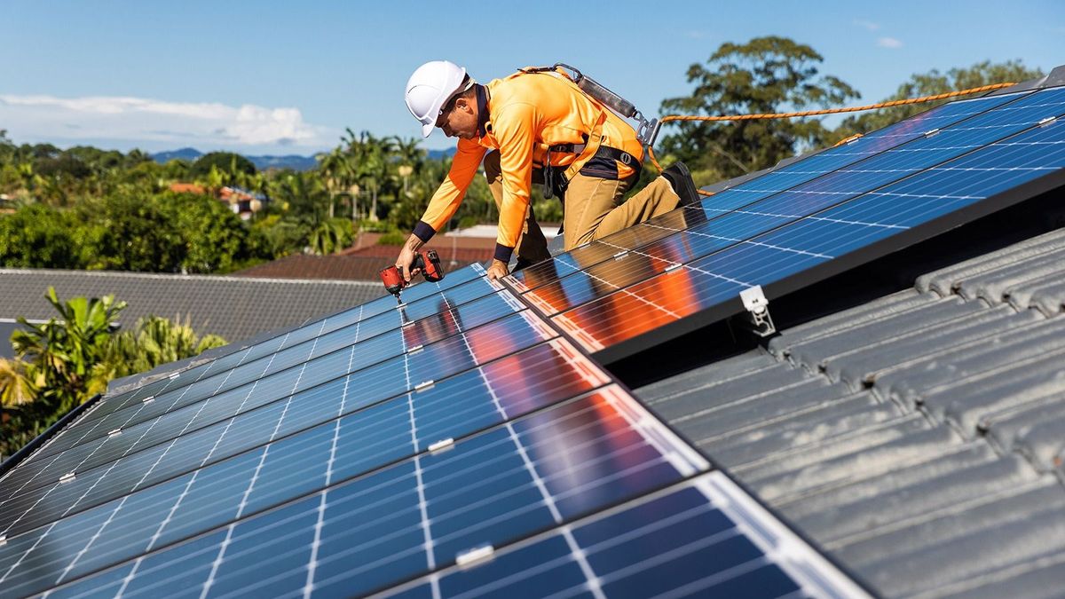 Solar,Panel,Technician,With,Drill,Installing,Solar,Panels,On,HouseSolar panel technician with drill installing solar panels on house roof on a sunny day, 