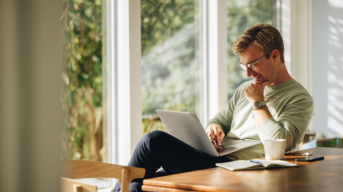 Young,Man,Using,Laptop,And,Smiling,At,Home.,Man,Sitting