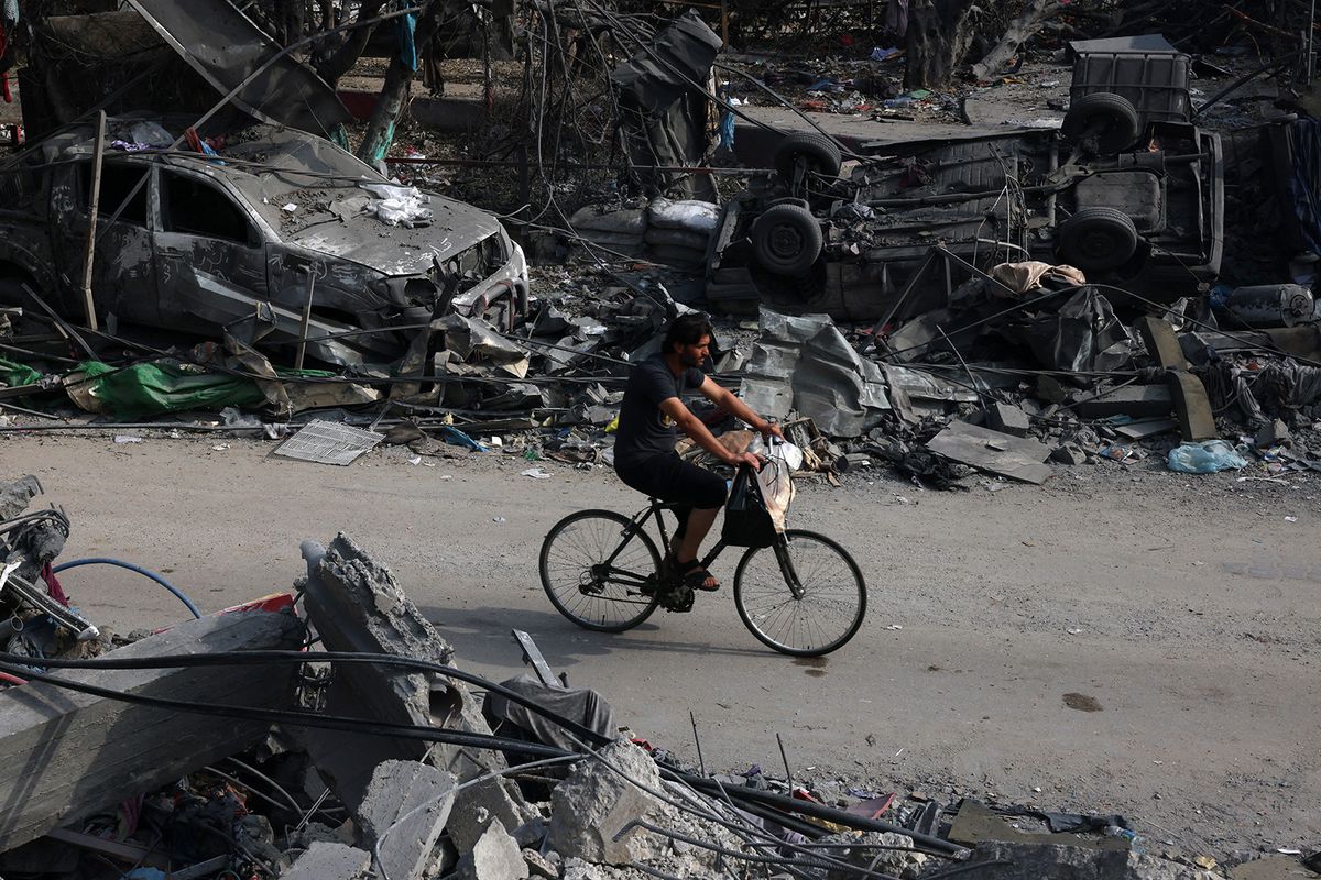 A youth rides a bicycle past wrecked cars in the aftermath of Israeli bombing in Rafah in the southern Gaza Strip on October 28, 2023. Since the October 7 Hamas attack on Israel, the health ministry in the Palestinian enclave said more than 7,300 Palestinians have been killed by Israel's relentless retaliatory bombardments, mainly civilians and many of them children. (Photo by SAID KHATIB / AFP)