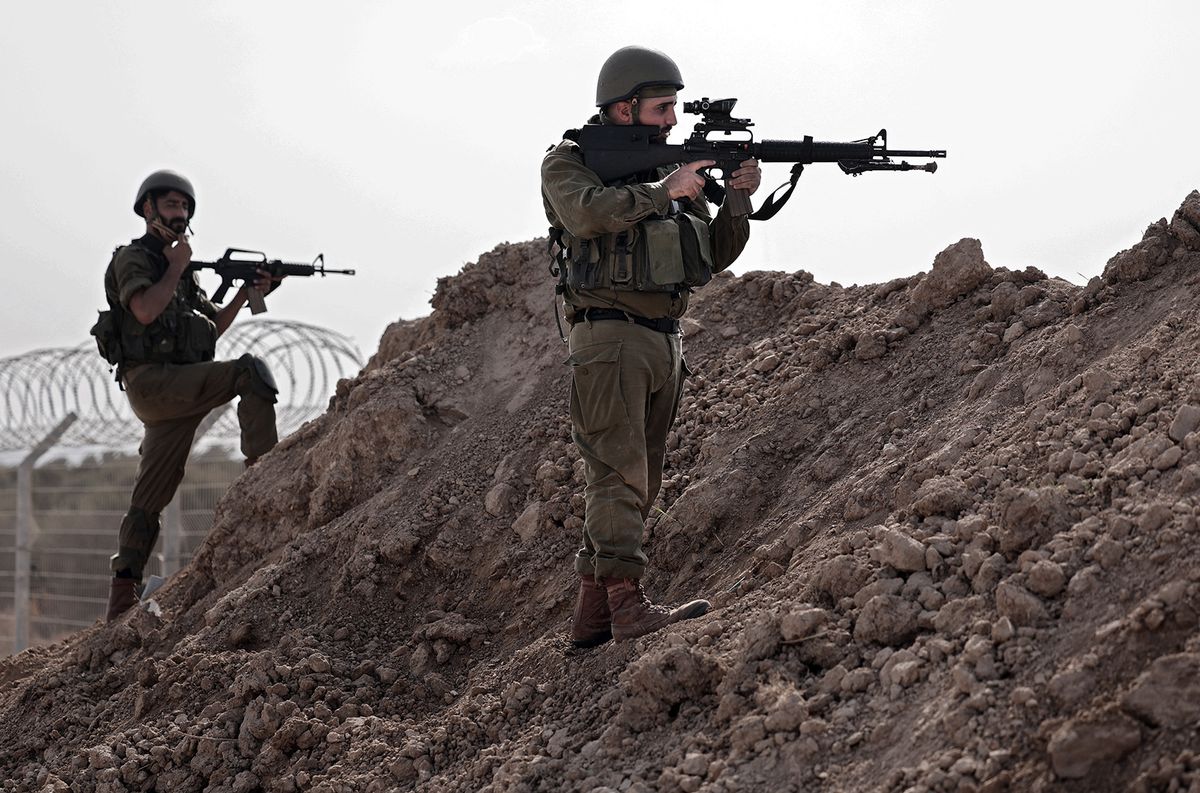 In this picture taken during a media tour organised by the Israeli military on October 22, 2023, Israeli soldiers take a defensive position in Kibbutz Beeri along the border with the Gaza Strip, in the aftermath of a Palestinian militant attack on October 7. (Photo by Thomas COEX / AFP)