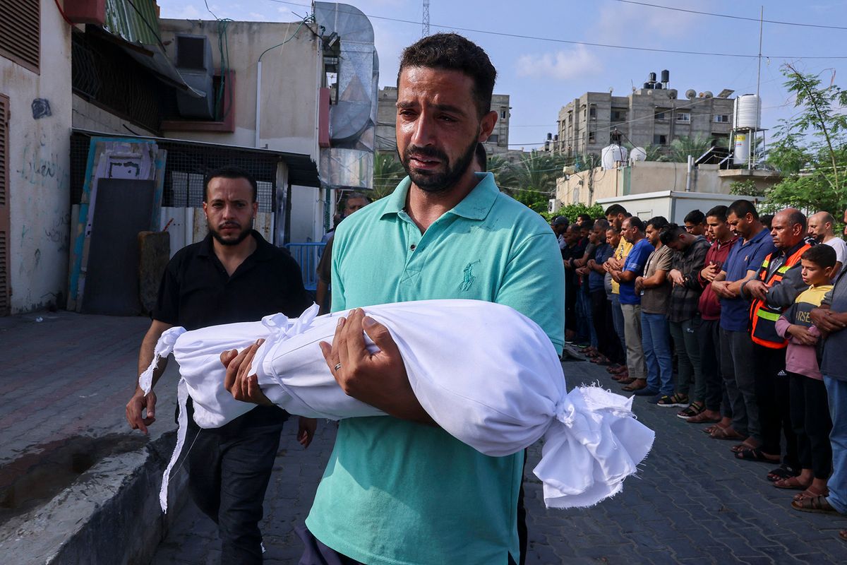 A Palestinian man carries the body of a child killed in overnight Israeli shelling during a funeral in Khan Yunis in the southern Gaza Strip, on October 10, 2023. Israel pounded Hamas targets in Gaza on October 10 and said the bodies of 1,500 Islamist militants were found in southern towns recaptured by the army in gruelling battles near the Palestinian enclave. (Photo by SAID KHATIB / AFP)